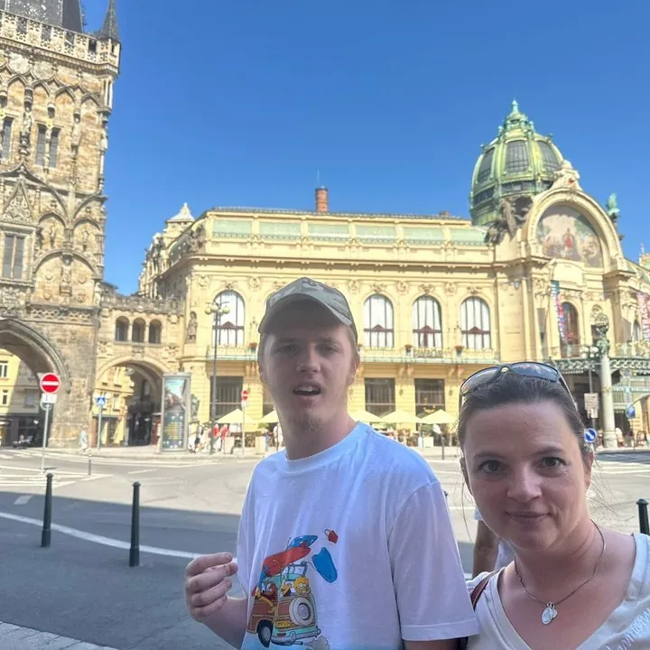 Mężczyzna i jego mama uśmiechnięta w słońcu na tle zabytkowej kamienicy